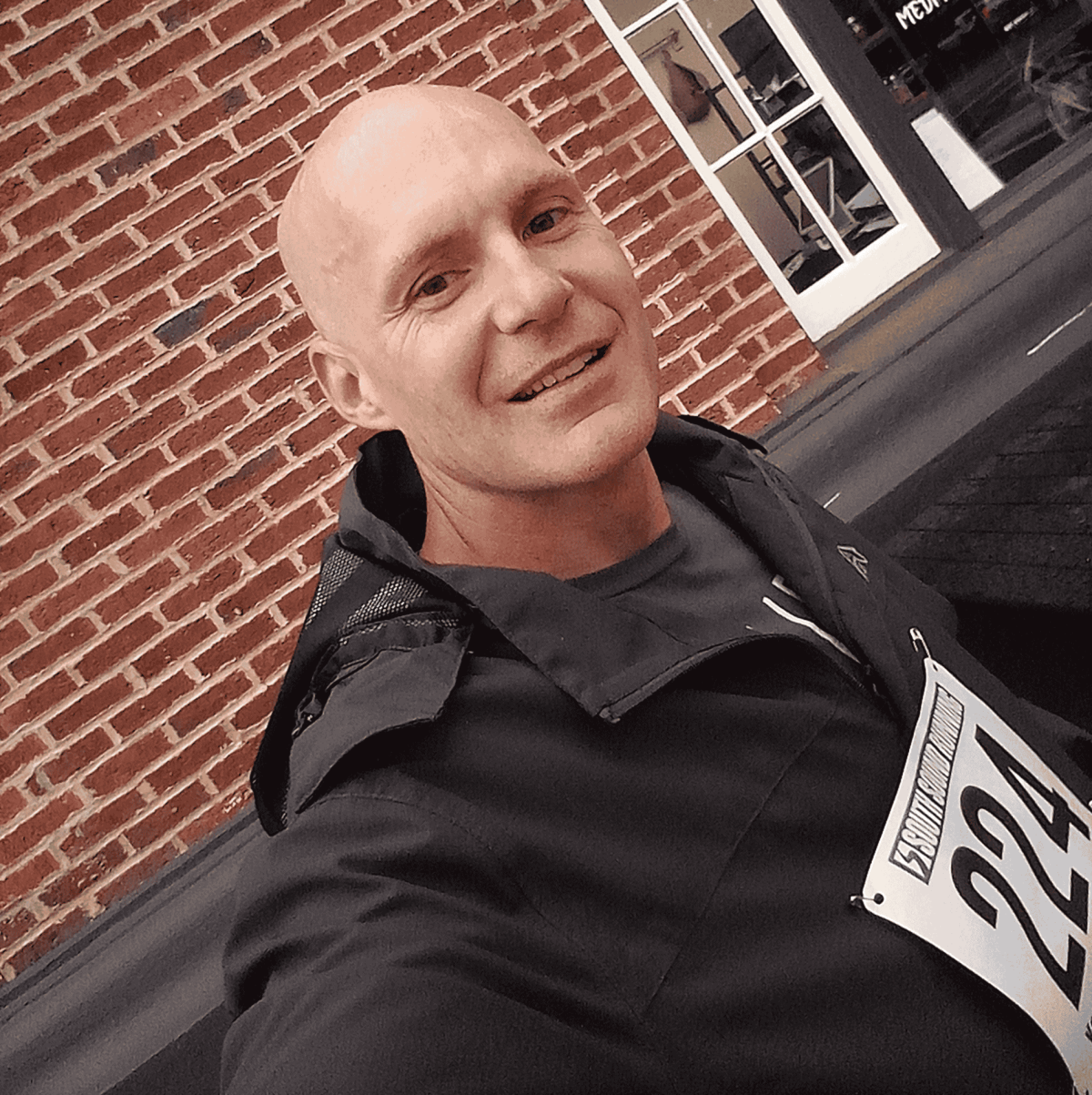 Male taking selfie while running a marathon in a black jacket